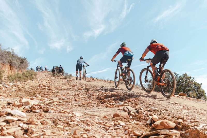 Mountain bikers climbing a rocky track under a blue sky