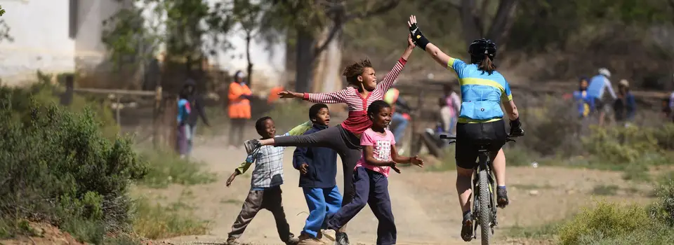 Children running alongside a rider to high-five her